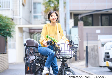 Mom riding a bicycle and shopping at a supermarket Mom riding a bicycle and shopping at a supermarket 86558606