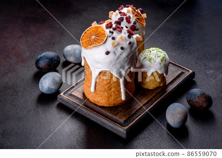 Festive cakes with white glaze, nuts and raisins with Easter eggs on the festive table Festive cakes with white glaze, nuts and raisins with Easter eggs on the festive table 86559070
