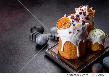 Festive cakes with white glaze, nuts and raisins with Easter eggs on the festive table 86559075