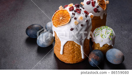 Festive cakes with white glaze, nuts and raisins with Easter eggs on the festive table Festive cakes with white glaze, nuts and raisins with Easter eggs on the festive table 86559080