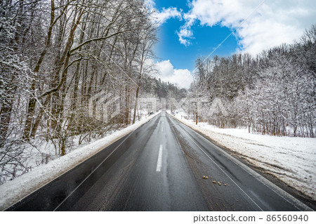 asphalt road in winter snowy forest, blue sky asphalt road in winter snowy forest, blue sky 86560940