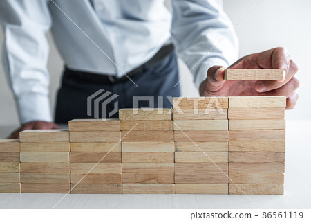 Risk To Make Business Growth Concept With Wooden Blocks, hand of businessman has piling up and stacking a wooden block, Alternative risk concept, plan and strategy in business 86561119