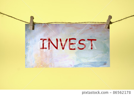 Invest text written on paper suspended from a rope on a yellow background ,business idea Invest text written on paper suspended from a rope on a yellow background ,business idea 86562178