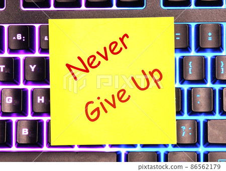 Never give up text written on a yellow sticker lies on a glowing keyboardbusiness 86562179
