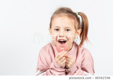 Adorable little girl puts myofunctional trainer in the mouth. 86562506