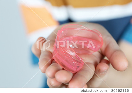 Cute little girl with blond hair is holding a pink dental myofunctional trainer Cute little girl with blond hair is holding a pink dental myofunctional trainer 86562516
