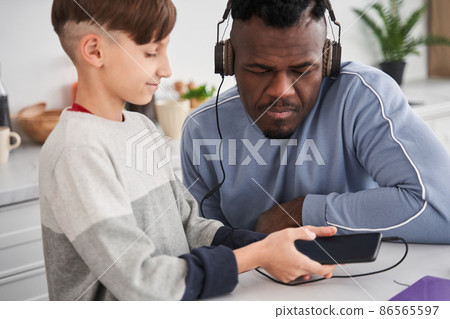 Multiracial man looking at the smartphone screen with serious face while choosing songs 86565597