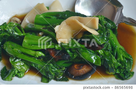 fried Chinese kale with slice abalone and black mushroom in soy sauce on plate 86565698