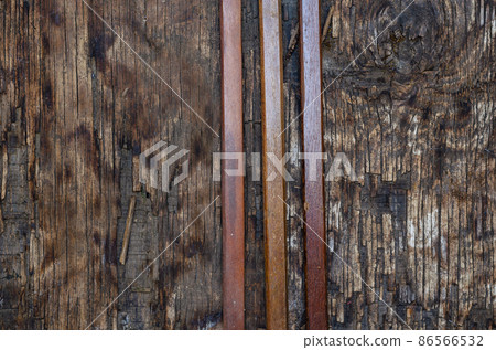 Three narrow wooden slats on a dark wooden background 86566532