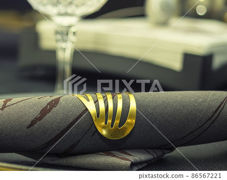 Black serving napkin with gold ring on the background of the glass Black serving napkin with gold ring on the background of the glass 86567221