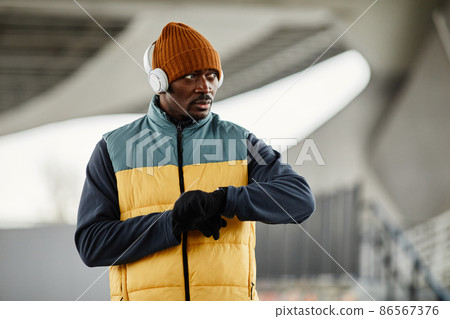 Black man in headphones over beanie hat 86567376