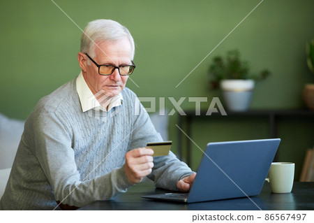 Modern senior man entering number of credit card during online payment Modern senior man entering number of credit card during online payment 86567497