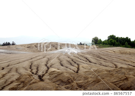 Muddy volcanoes. View of the muddy volcanoes with their unusual geology and cracked texture of the dry mud. Romania, out of focus. Muddy volcanoes. View of the muddy volcanoes with their unusual geology and cracked texture of the dry mud. Romania, out of focus. 86567557