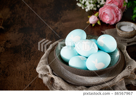 Unusual Easter on dark old background. Ceramic brown bowl with blue eggs. Unusual Easter on dark old background. Ceramic brown bowl with blue eggs. 86567967