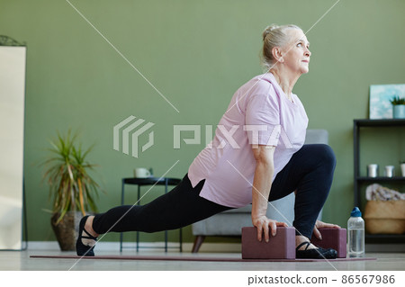 Active senior female with yoga blocks exercising on the floor 86567986