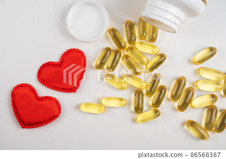 Gold fish oil isolated on white background with red hearts. Gold fish oil isolated on white background with red hearts. 86568387