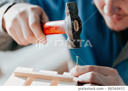 Young Caucasian carpenter in working clothes makes wooden boxes in carpentry workshop. Hands with Young Caucasian carpenter in working clothes makes wooden boxes in carpentry workshop. Hands with 86568431