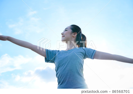 一位穿著訓練服的年輕女子在藍天下做瑜伽 86568701