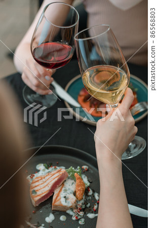 Celebration, two women with glasses of red and white wine in a restaurant on a holiday. Celebration, two women with glasses of red and white wine in a restaurant on a holiday. 86568803