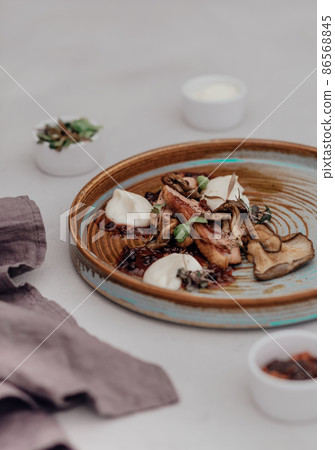 Fillet of beef with mushroom sauce on a light background. Microgreens in small gravy boat Fillet of beef with mushroom sauce on a light background. Microgreens in small gravy boat 86568845