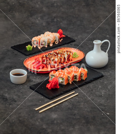 Sushi roll with chopsticks on a stone stand on a on a black stand. Sushi menu. Sushi roll with chopsticks on a stone stand on a on a black stand. Sushi menu. 86568865