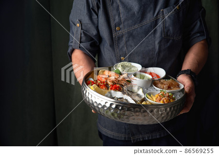 Metal tray with open oysters, raw mussels in the chef's hands. Assorted seafood. Free space for text Metal tray with open oysters, raw mussels in the chef's hands. Assorted seafood. Free space for text 86569255