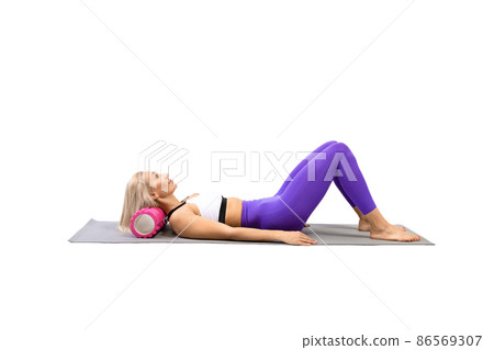 Neck and trapezius muscles extension. Adult fit woman lying on back and using pilates roller to stretch her muscle, isolated on white. 86569307