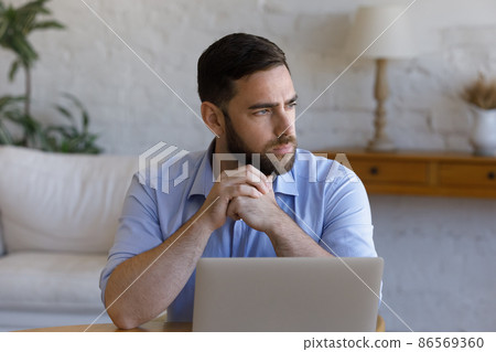 Serious thoughtful business man working at table with laptop 86569360