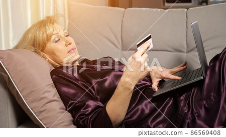 Middle aged woman pays for purchases online via laptop 86569408