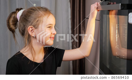 Teenager girl waits for food preparing in stove at home Teenager girl waits for food preparing in stove at home 86569410