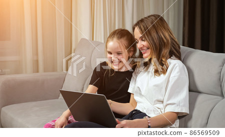 Happy mother and teen daughter watch funny photos on laptop Happy mother and teen daughter watch funny photos on laptop 86569509