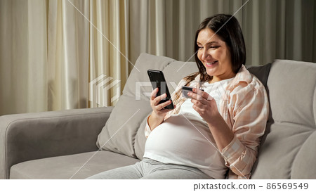 Brunette pregnant woman pays for online shopping via phone Brunette pregnant woman pays for online shopping via phone 86569549