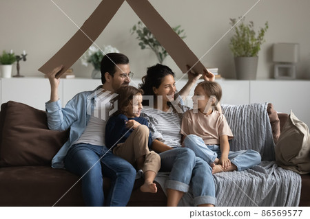 Couple with children sitting on sofa holding carton like roof 86569577