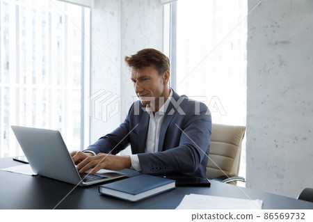Serious busy middle aged businessman typing on laptop at workplace Serious busy middle aged businessman typing on laptop at workplace 86569732