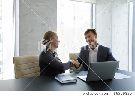 Happy confident business partners in formalwear shaking hands after negotiation Happy confident business partners in formalwear shaking hands after negotiation 86569850