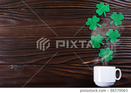 Coffee cup with three leaved shamrock handmade leaves on wooden background Coffee cup with three leaved shamrock handmade leaves on wooden background 86570065