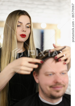 Stylish woman hairdresser combing hair to a man Stylish woman hairdresser combing hair to a man 86570067