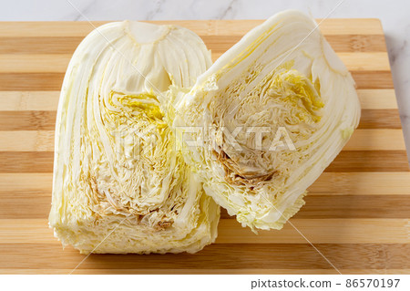 Rotten napa cabbage cut in half on a chopping board. 86570197