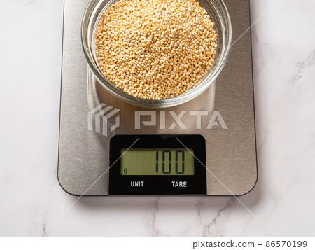 Raw dry quinoa in a glass bowl on a digital kitchen scale. Raw dry quinoa in a glass bowl on a digital kitchen scale. 86570199