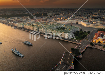 Aerial landscape with warships in the Neva River before the holiday of the Russian Navy at early morning, warships pass under a raised drawbridge, the latest cruisers among landmarks, Palace bridge 86570526