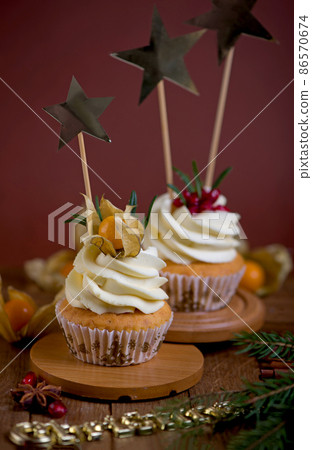 Christmas cupcakes with vanilla frosting, cranberries and rosemary on wooden background. Selective focus Christmas cupcakes with vanilla frosting, cranberries and rosemary on wooden background. Selective focus 86570674