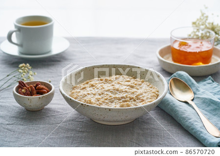 Whole oatmeal, large bowl of porridge with butter for breakfast, morning meal. Side view 86570720