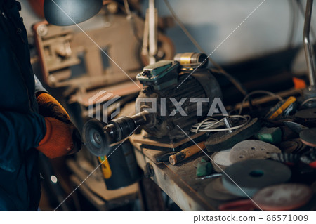 Blacksmith forges and cleaning arrow metal detail with hammer and anvil at forge. 86571009