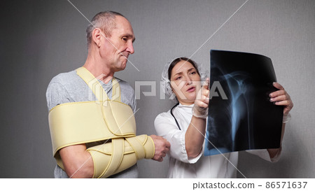 Orthopedist shows x-ray photograph to patient with bandage Orthopedist shows x-ray photograph to patient with bandage 86571637