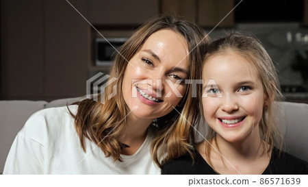 Mother and daughter smile widely looking in camera at home Mother and daughter smile widely looking in camera at home 86571639
