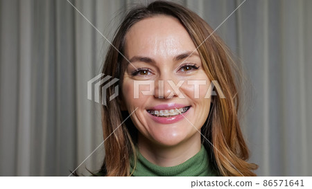Young brunette woman with braces on teeth smiles widely Young brunette woman with braces on teeth smiles widely 86571641