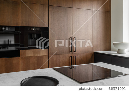 Modern minimalistic kitchen with black and wooden surfaces, marble kitchen island top and household appliances. Modern Concept For Interior Design And Architecture. Modern minimalistic kitchen with black and wooden surfaces, marble kitchen island top and household appliances. Modern Concept For Interior Design And Architecture. 86571991