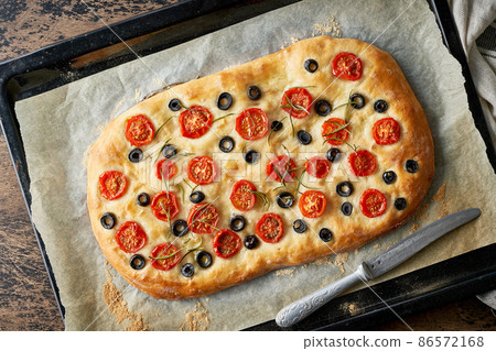 Focaccia, pizza, italian flat bread with tomatoes, olives and rosemary on tray 86572168