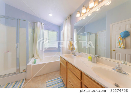 Bathroom with light blue walls and windows at the corner with curtains Bathroom with light blue walls and windows at the corner with curtains 86574768
