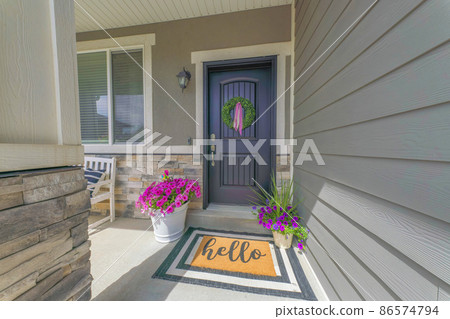 Black front door of a house with wreath and potted flowers at the front Black front door of a house with wreath and potted flowers at the front 86574794